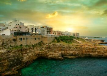 white concrete building on cliff by the sea under blue sky during daytime