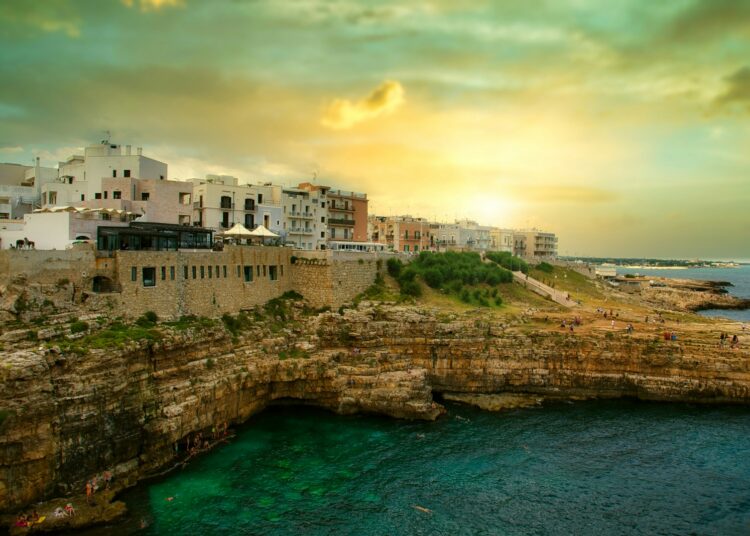white concrete building on cliff by the sea under blue sky during daytime