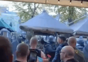 ME lopen langs een terras en spuiten pepperspray richting mensen.